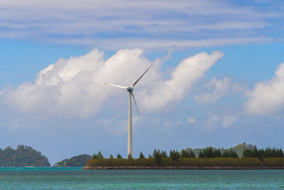 Wind turbines in water against sky