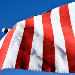 Close-up of flag hanging against blue sky