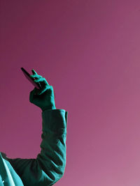 Midsection of person holding umbrella against pink wall