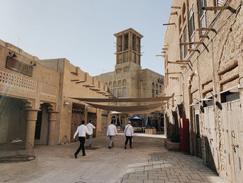 Rear view of people walking on street amidst buildings in city