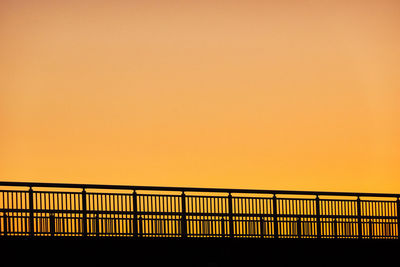 Silhouette bridge railing against sky during sunset