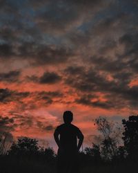 Silhouette man standing against orange sky