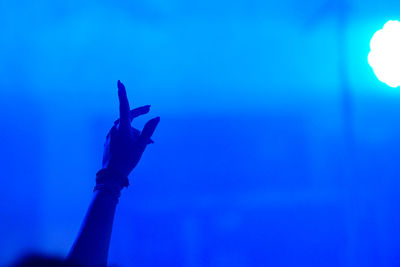 Close-up of silhouette hand against blue sky