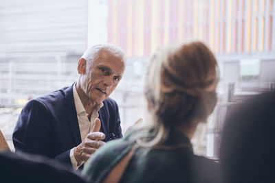 Confident mature businessman discussing with businesswoman during meeting at creative office