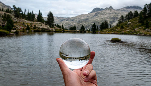 Midsection of person holding ice over lake