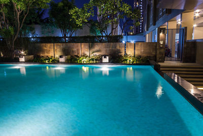 Swimming pool by building at night