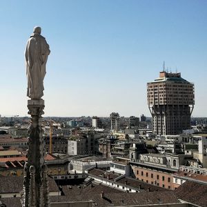 Statue in city against clear sky