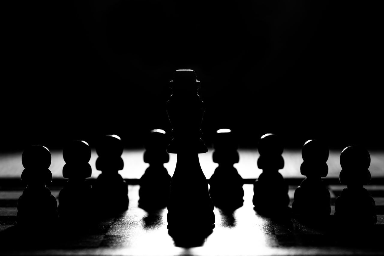 CLOSE-UP OF CHESS PIECES AGAINST SILHOUETTE BACKGROUND