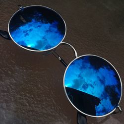 Close-up of sunglasses against blue sky