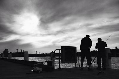 Man looking at sea against cloudy sky