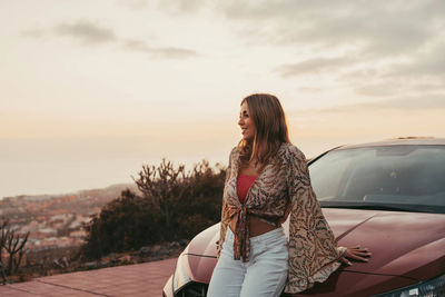 Rear view of woman standing against sky during sunset