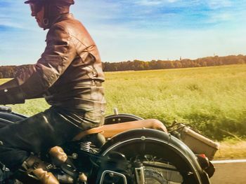 Man riding motorcycle on field against sky