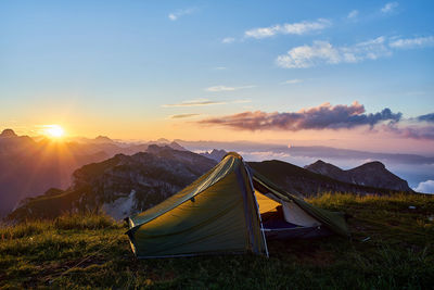 Tent on field against sky during sunset