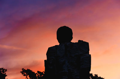 Low angle view of silhouette man standing against orange sky