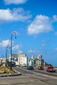 Cars on road by buildings against sky