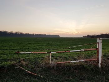Fence on field against sky during sunset