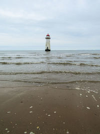 Lighthouse by sea against sky