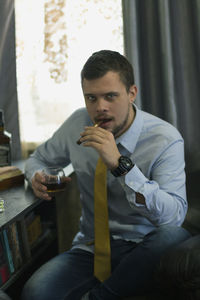 Man holding cigarette while sitting on table