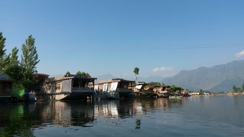 Houses by lake and buildings against clear sky