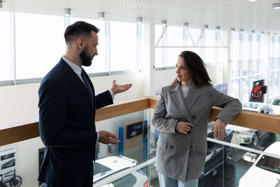 Car salesman talking with customer at showroom