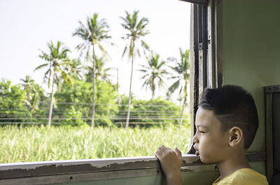Close-up of boy looking through window of train