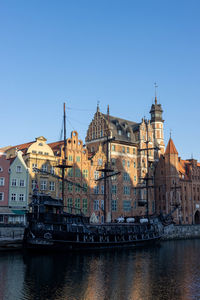 River by buildings in city against clear sky