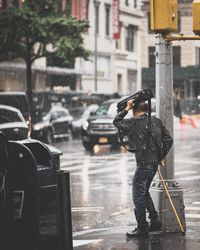 Man holding umbrella on city street during rainy season