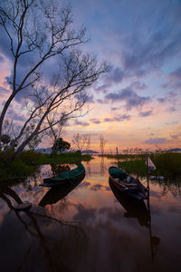 Boat moored in lake against sky during sunset