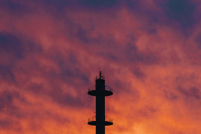 Low angle view of silhouette tower against orange sky