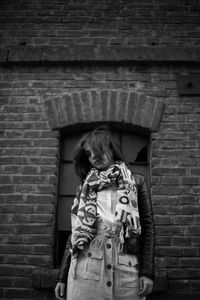 Full length of girl standing against brick wall