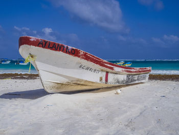 Boat moored on beach against sky