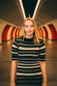 Portrait of young woman standing in illuminated tunnel