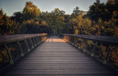 Footbridge amidst trees against sky during autumn