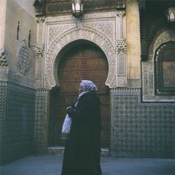 Rear view of woman standing at entrance of historic building