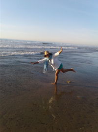 Full length of man jumping on beach against clear sky