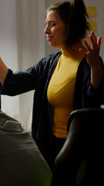 Young woman looking away while sitting at home