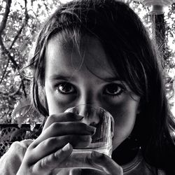 Close-up of girl drinking water from glass in park