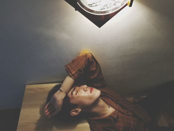 High angle view of young woman relaxing by wall at home