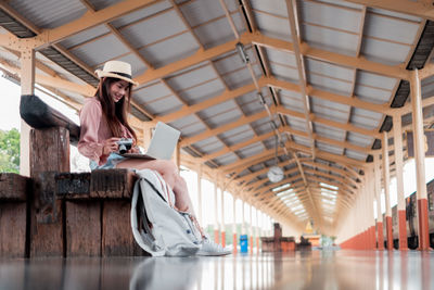 Full length of woman sitting on mobile phone