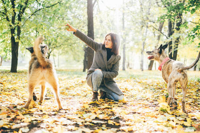 Side view of woman with dogs on field