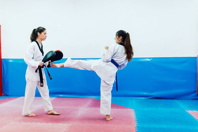 Two young women practice taekwondo in a training center