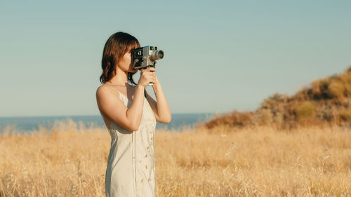 Pretty girl with vintage 8mm camera in the countryside