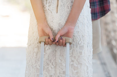 Midsection of woman standing against white wall