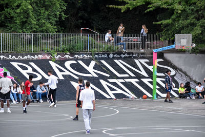 Rear view of people walking on basketball court