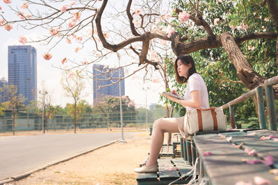Woman sitting in park by city