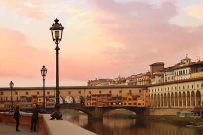 Street lights by bridge against sky during sunset