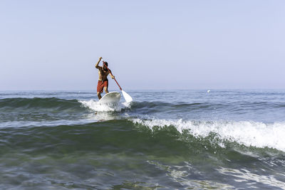 Man surfing on sea against clear sky