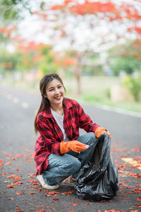 Portrait of smiling young woman sitting during autumn