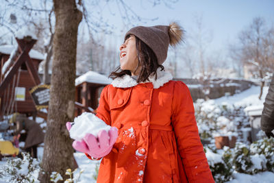 Rear view of woman standing against trees during winter