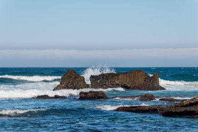 Rocks on sea shore against sky